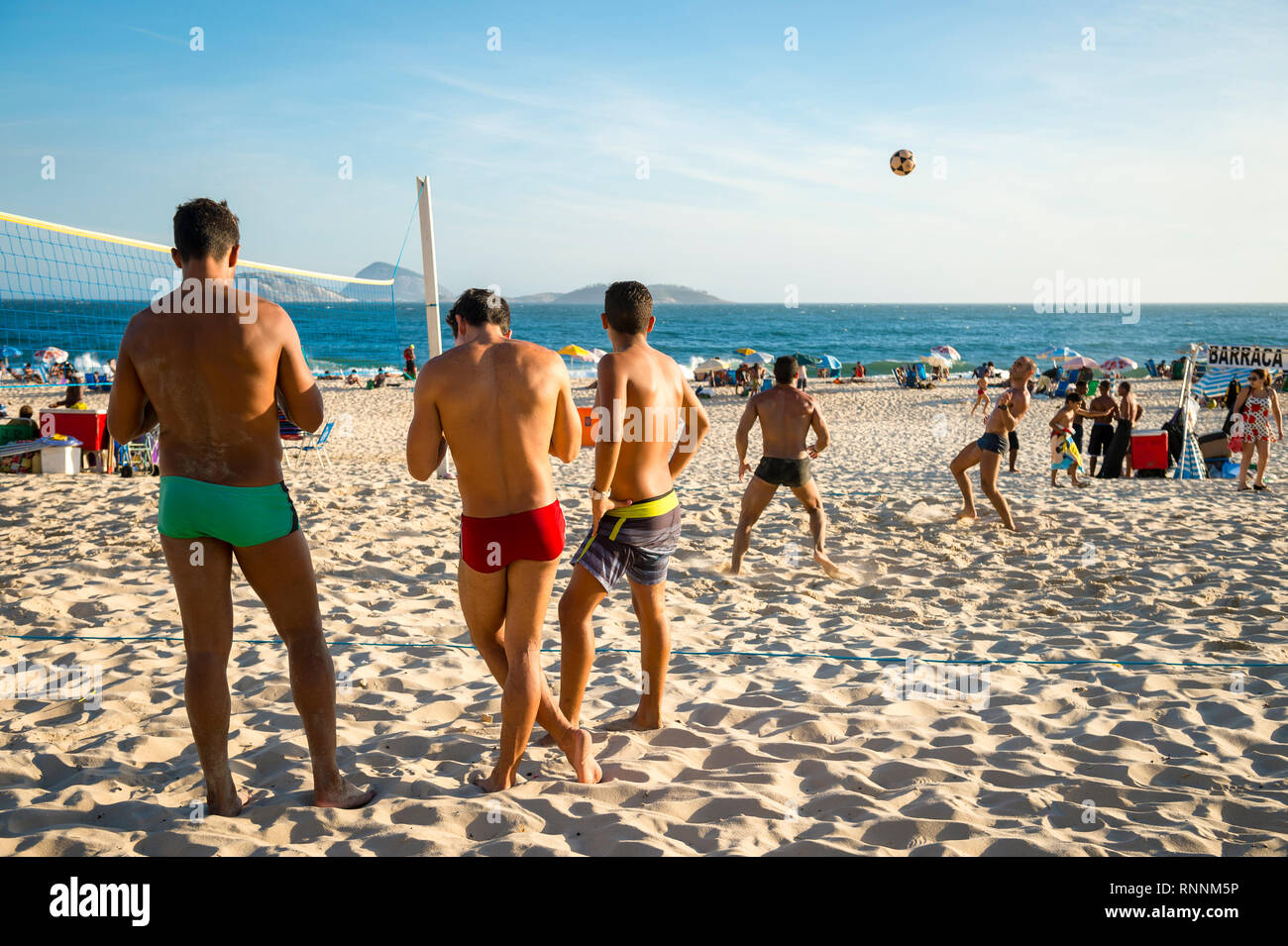 RIO DE JANEIRO - JANUARY 2017: A group of young Brazilian men play foot volley, a hybrid sport of volleyball and soccer without hands or arms. Stock Photo