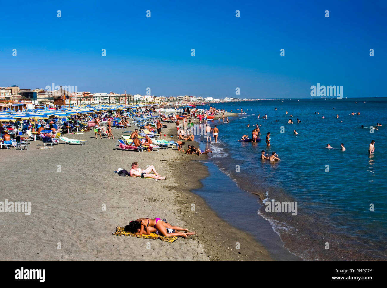beach scene; sand; water; people; umbrellas; buildings, relaxation; vacation; Tyrrhenian Sea; Ostia; Italy; summer; horizontal Stock Photo