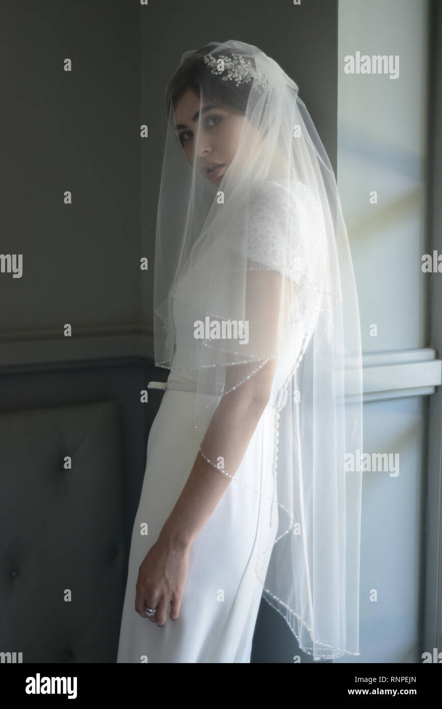 A young pensive couple have a traditional English White Wedding, they are both dark haired and good looking but seem unhappy Stock Photo