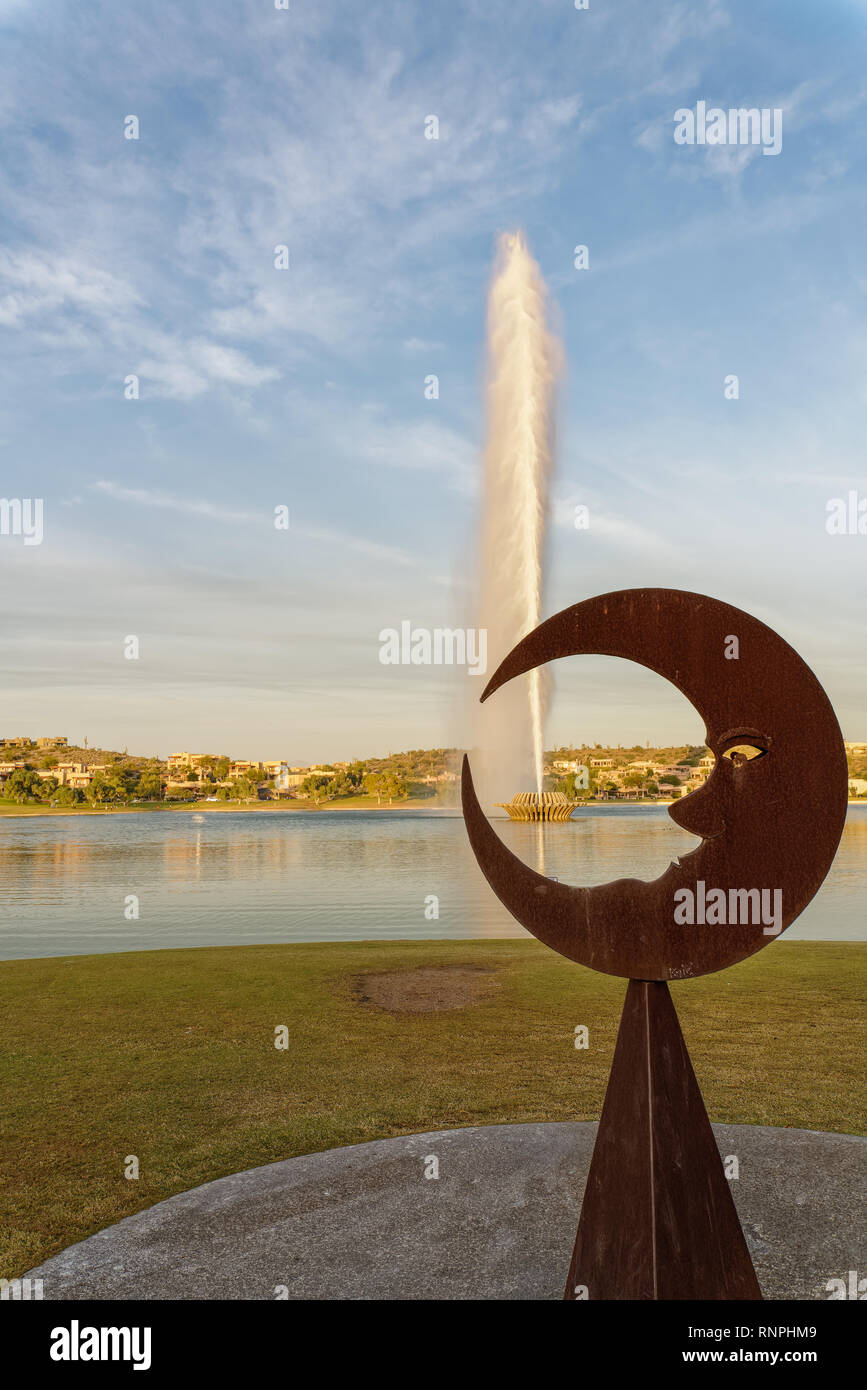 The Man in the Moon sculpture is framing the lotus shape base of the fountain as it goes off. Stock Photo