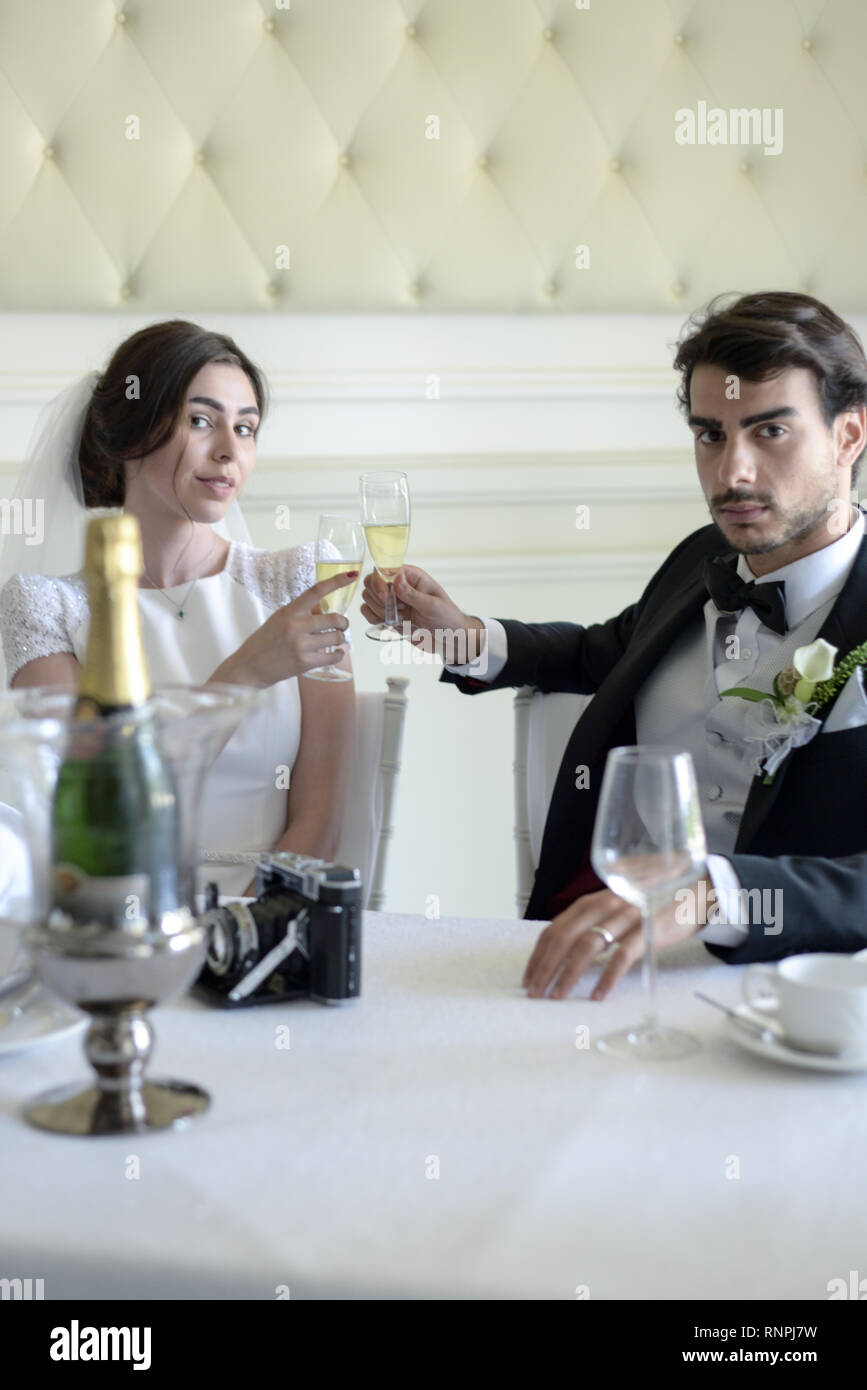 A young pensive couple have a traditional English White Wedding, they are both dark haired and good looking but seem unhappy Stock Photo