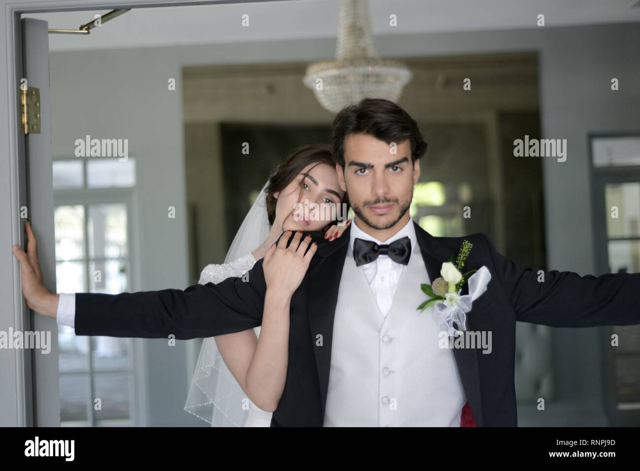 A young pensive couple have a traditional English White Wedding, they are both dark haired and good looking but seem unhappy Stock Photo
