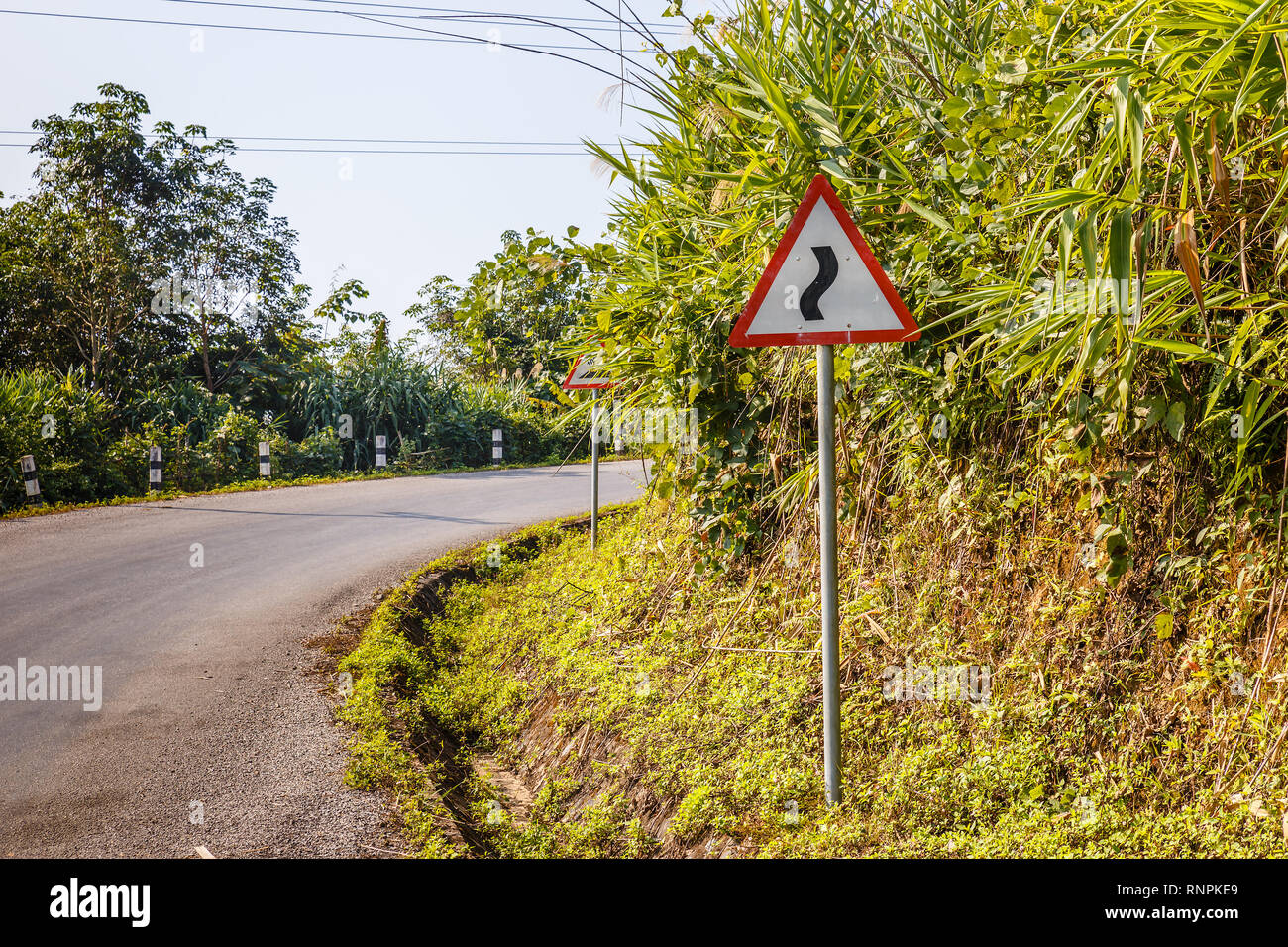 sign winding road on a mountain road, warning traffic sign Laos Stock Photo