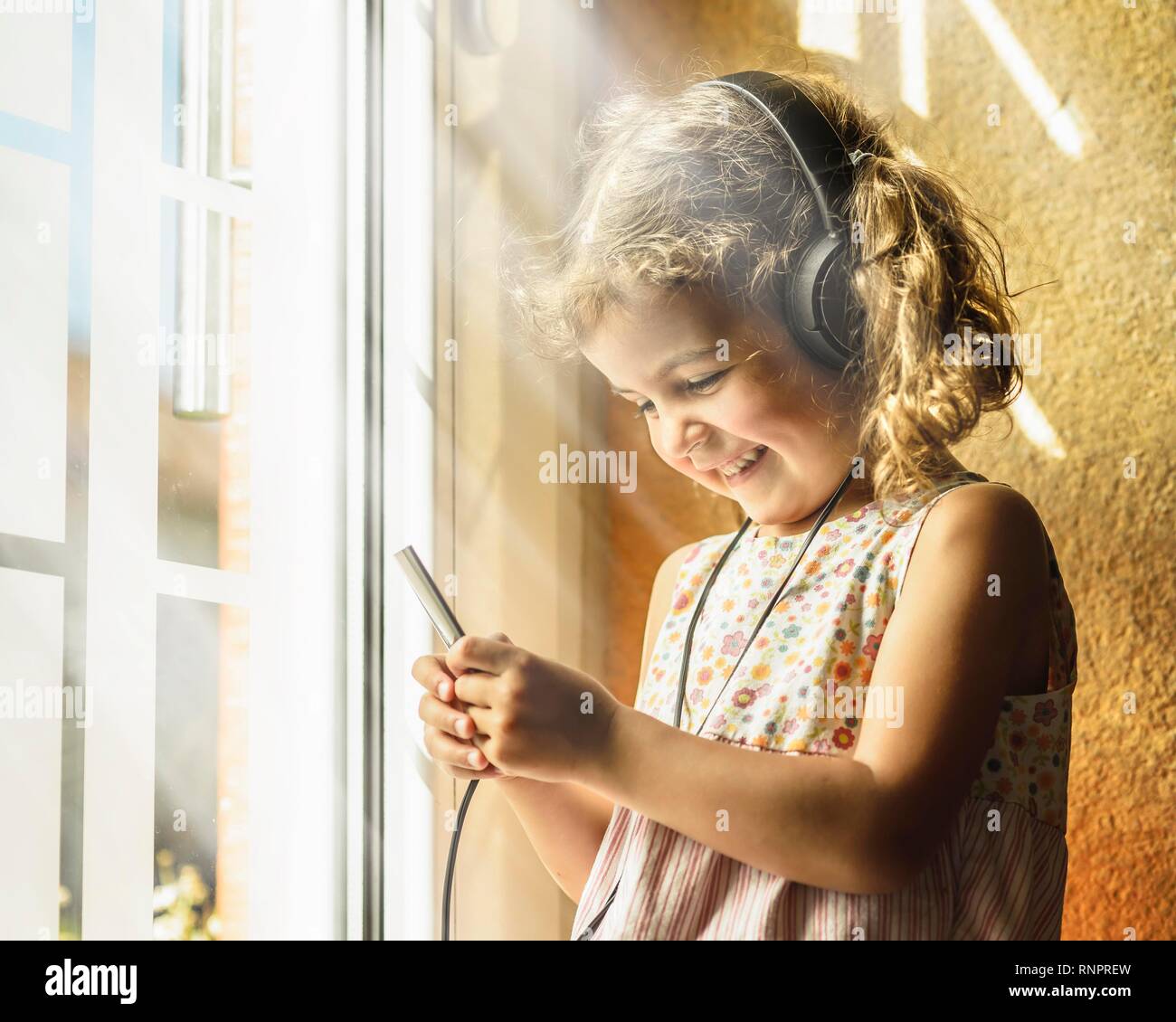 Girl, 3 years, listens to music with headphones, good mood, Germany Stock Photo