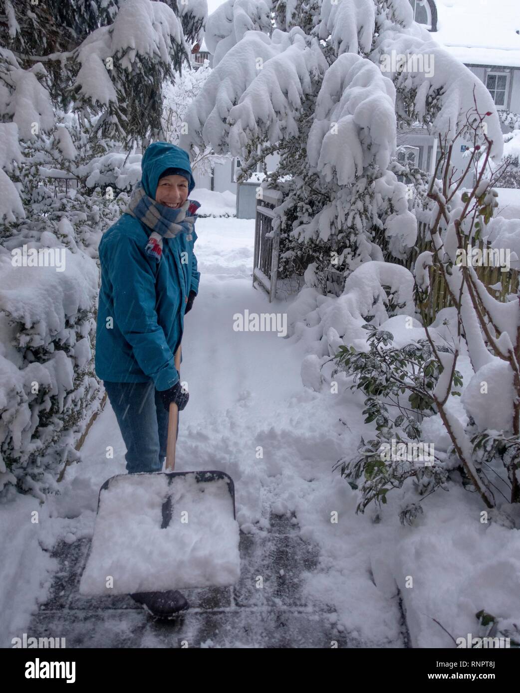 Woman with a snow shovel clearing snow, Munich, Bavaria, Germany Stock Photo