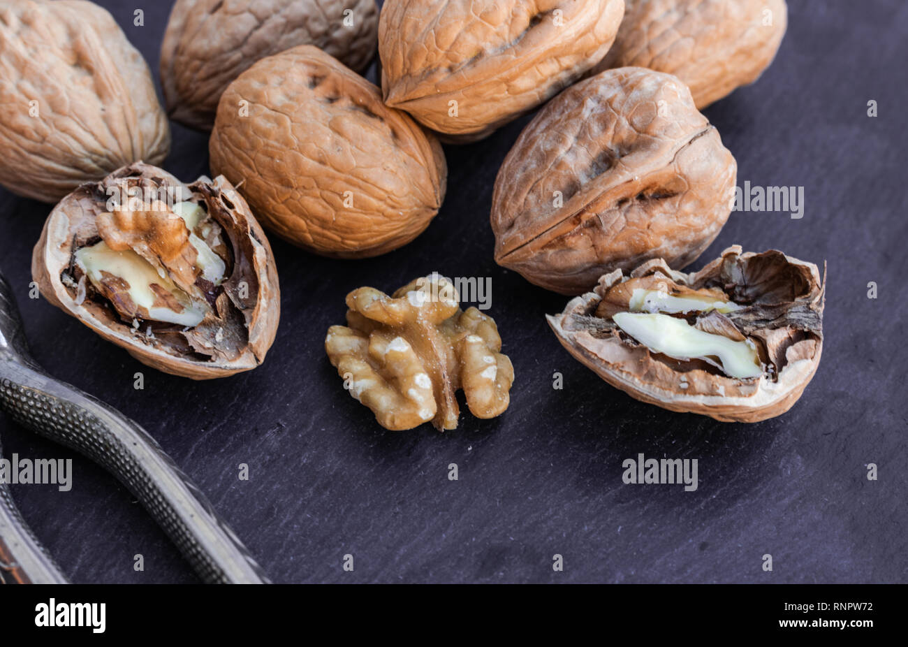 Walnuts with nutcracker, on black surface Stock Photo