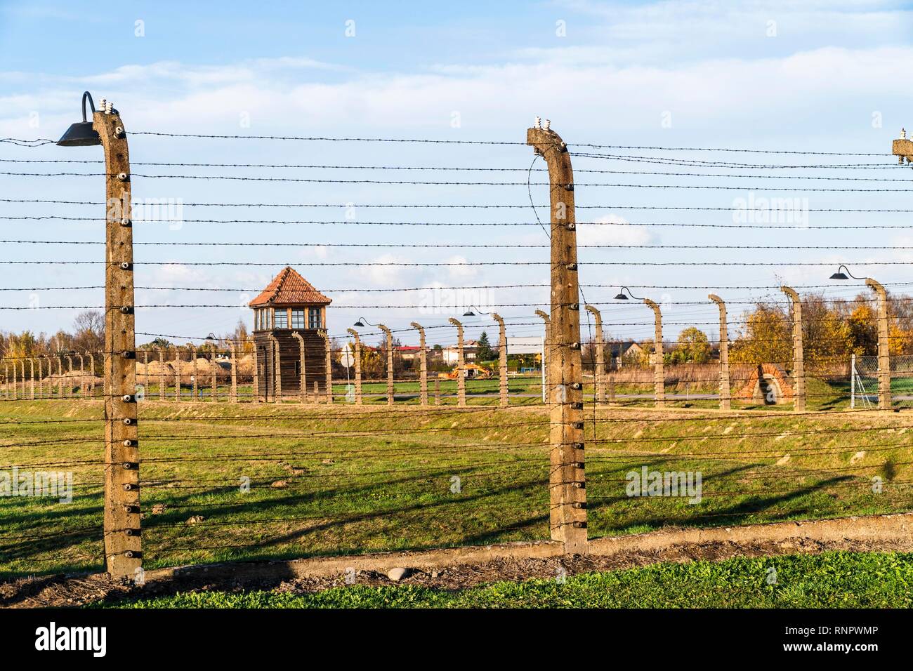 Barbed wire fence with watchtower surrounding Auschwitz concentration camp, Poland Stock Photo