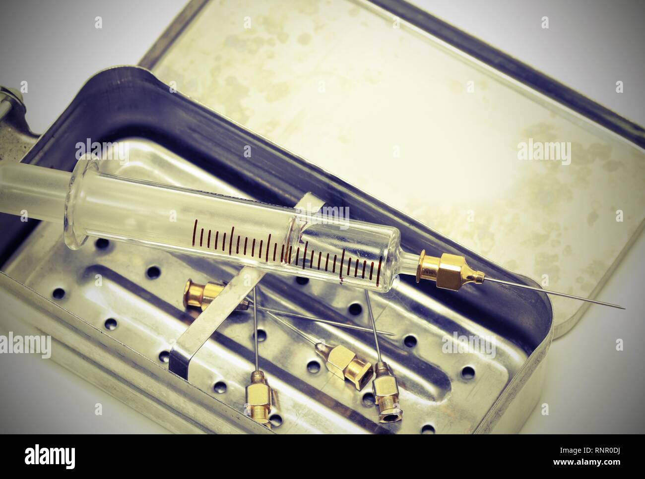 very old syringe in glass material and the vintage toned effect with metal case and more neddles Stock Photo