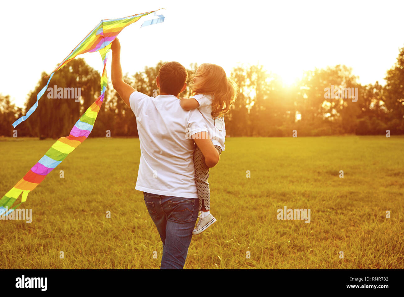 happy family father and child run on meadow with a kite in the summer on the nature Stock Photo