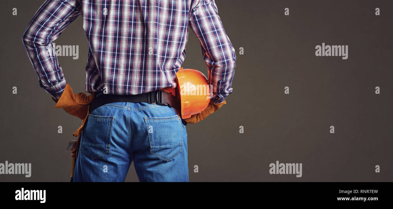 Builder man in plaid shirt and gloves wearing and holding helmet Stock Photo