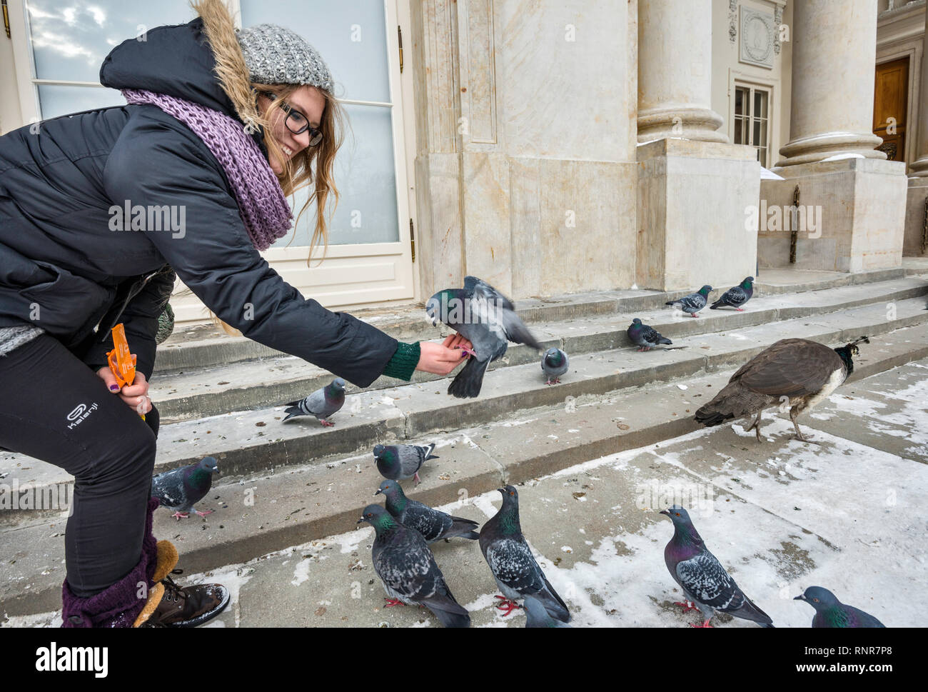 Young woman feeding a pigeon at Lazienki Palace in Warsaw, Poland Stock Photo