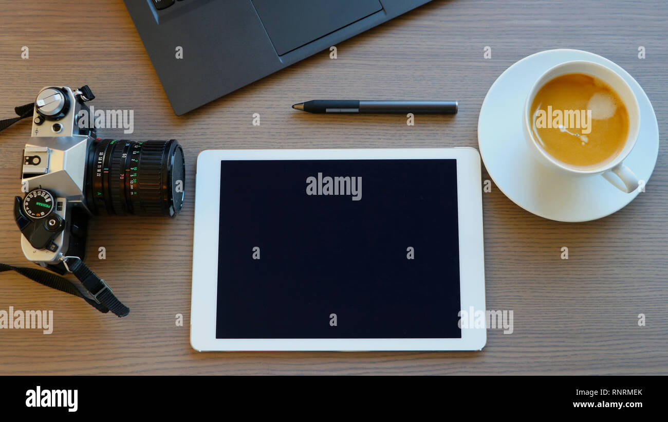 Office desk with film camera, pad, touch pen, computer, coffee, top view Stock Photo