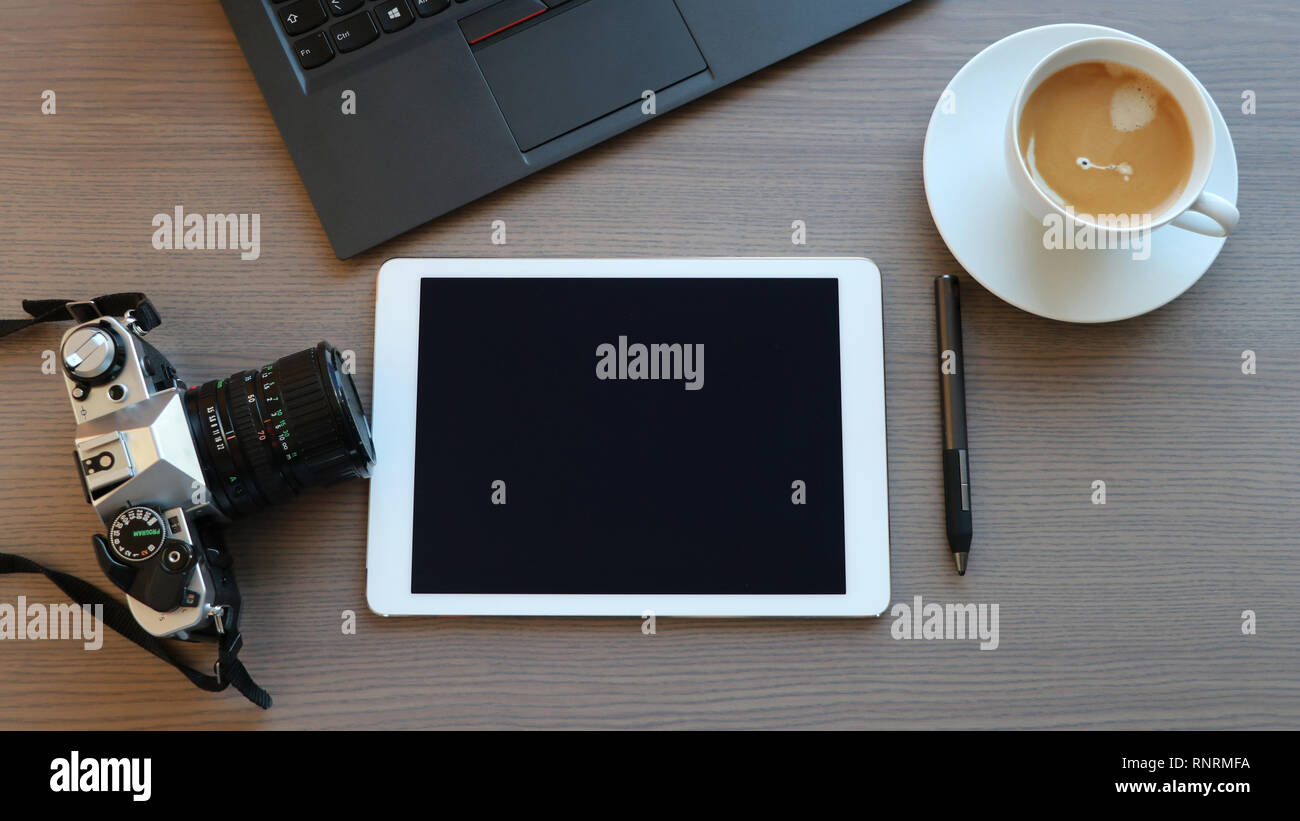 Office desk with film camera, pad, touch pen, computer, coffee, top view Stock Photo