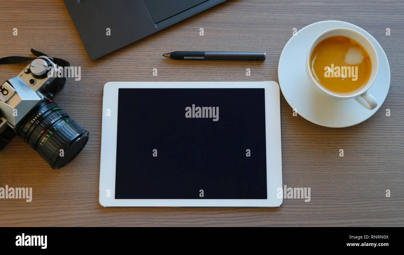 Office desk with film camera, pad, touch pen, computer, coffee, top view Stock Photo