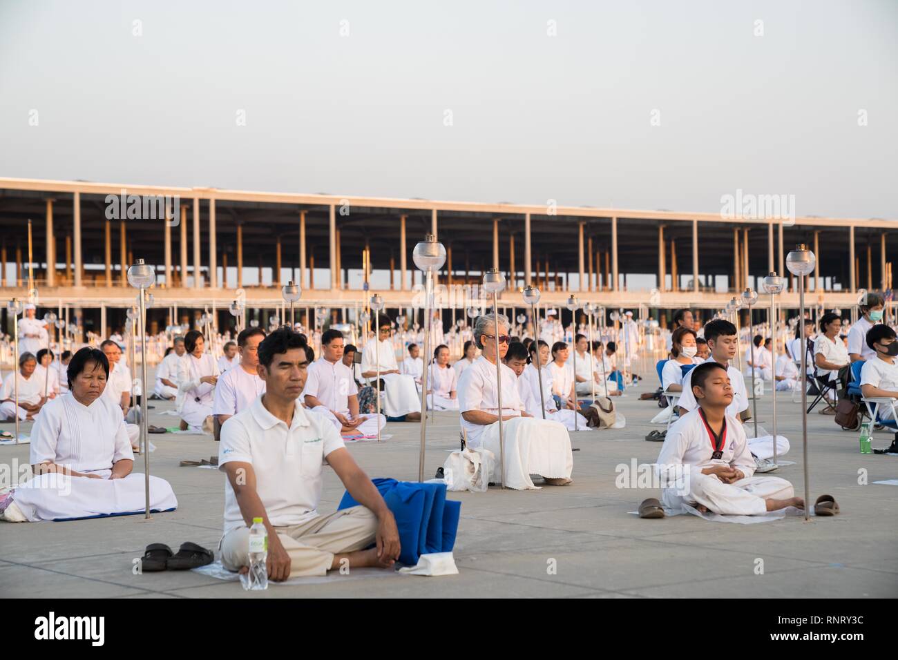 Devotees seen meditating during the yearly Makha Bucha ceremony. Buddhist devotees celebrate the annual festival of Makha Bucha, one of the most important day for buddhists around the world. More than a thousand monks and hundred of thousand devotees were gathering at Dhammakaya Temple in Bangkok to attend the lighting ceremony. Stock Photo