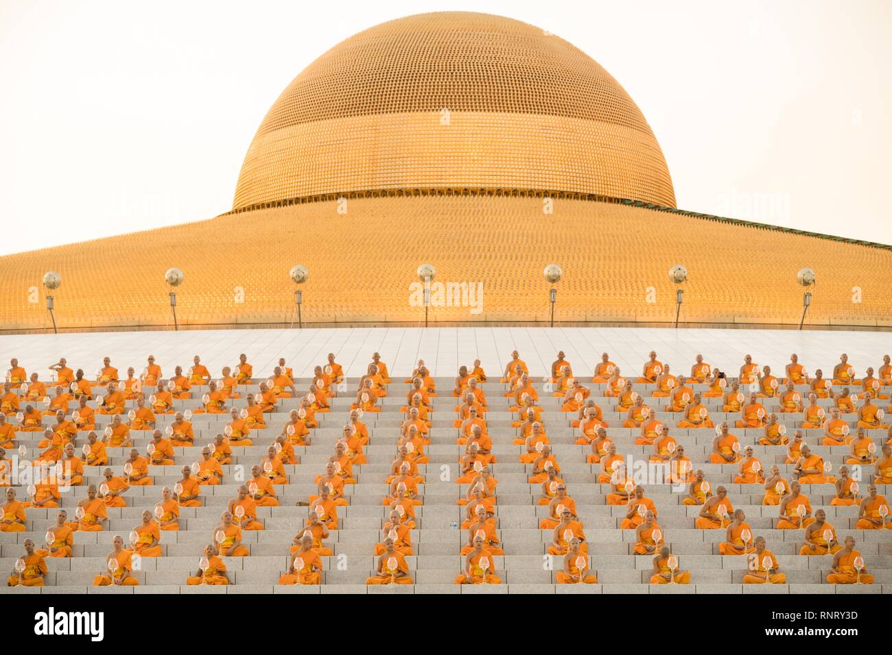 Monks seen praying while holding lanterns during the yearly Makha Bucha ceremony. Buddhist devotees celebrate the annual festival of Makha Bucha, one of the most important day for buddhists around the world. More than a thousand monks and hundred of thousand devotees were gathering at Dhammakaya Temple in Bangkok to attend the lighting ceremony. Stock Photo