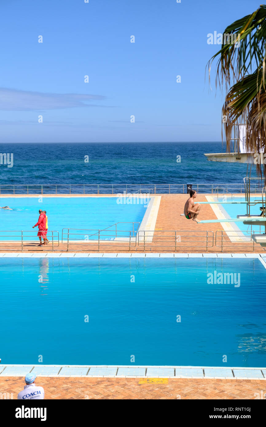 A man preparing to jump backwards from a diving board at Sea Point Pavilion, Cape Town, South Africa Stock Photo