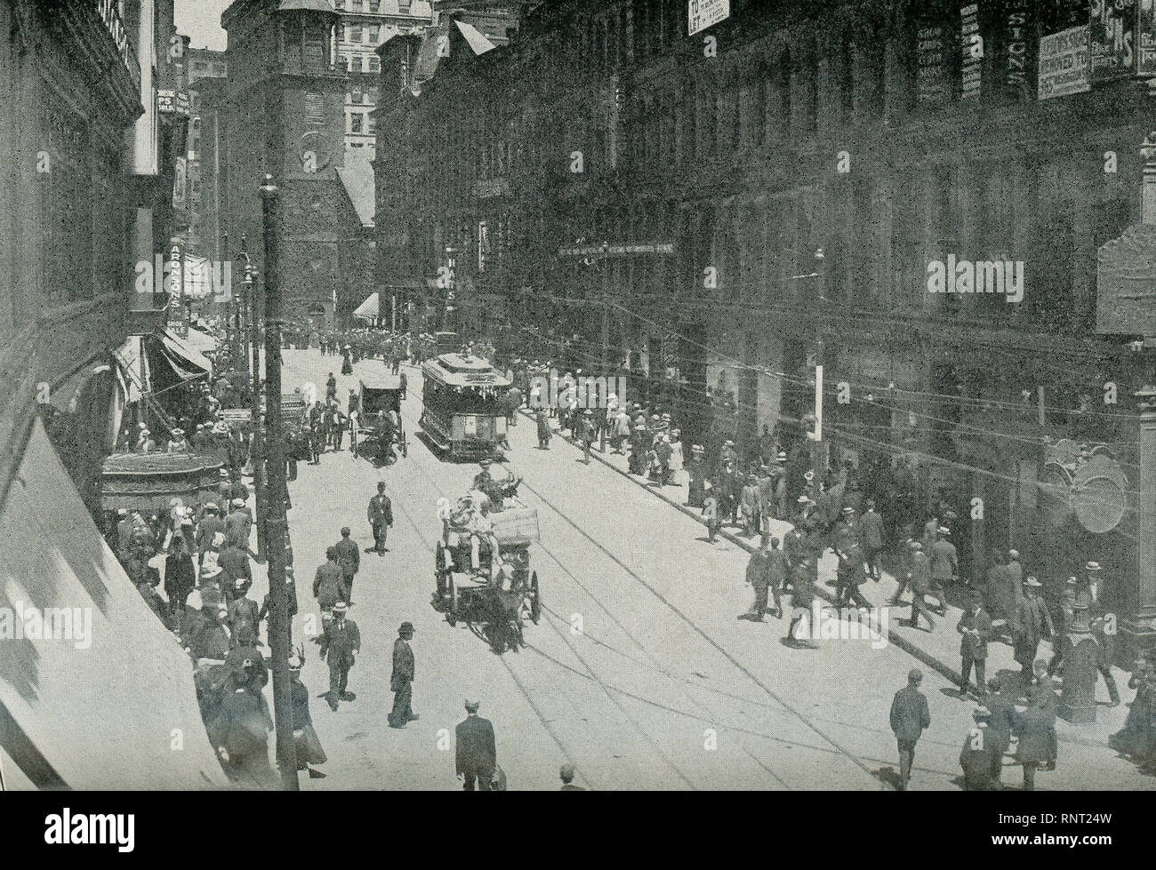 This photo dates to 1922 and shows Washington Street in Boston, Massachusetts. The caption reads: The Principal business street of Boston, named in honor of General Washington when the Continental troops occupied the city in 1776, after the withdrawal of the British forces. On this thoroughfare are located many of the largest business houses, finest theatres, ands the great newspaper offices. The daily traffic is enormous. Stock Photo