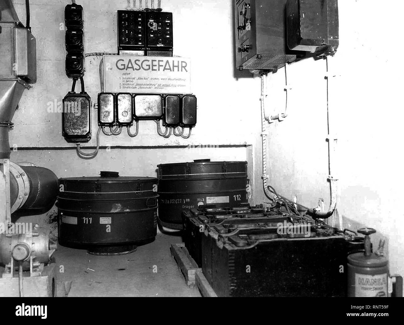 Original Caption: An abandoned German installation in the hills northwest of Soissons, shows the air conditioning and gas filtering unit inside the air raid bunkers. Intake and outlet pipes are on the left. Spare filter units are shown lower center, below the switchboard and fuse boxes. On wall to right is master control box, above row of batteries for emergency power. Stock Photo