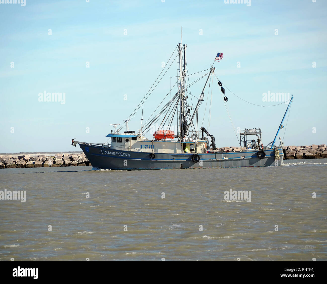 The shrimp boat, ' Kimberly Dawn,' passes through the Corpus Christi Ship Channel near the north jetty in Port Aransas, Texas USA. Stock Photo