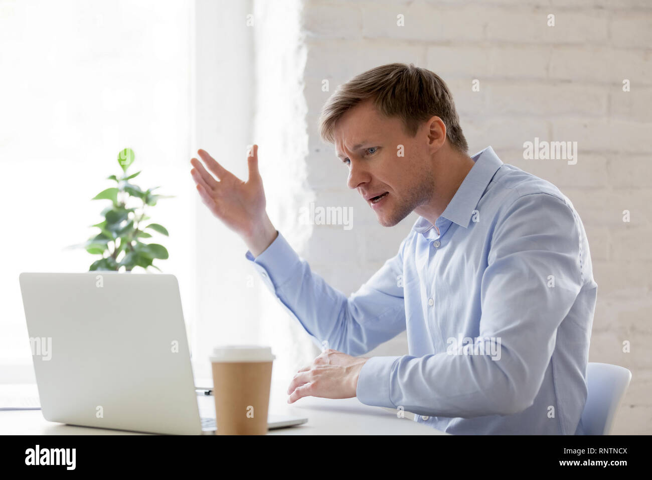 Irritated businessman having problems with computer gesticulating feels angry  Stock Photo