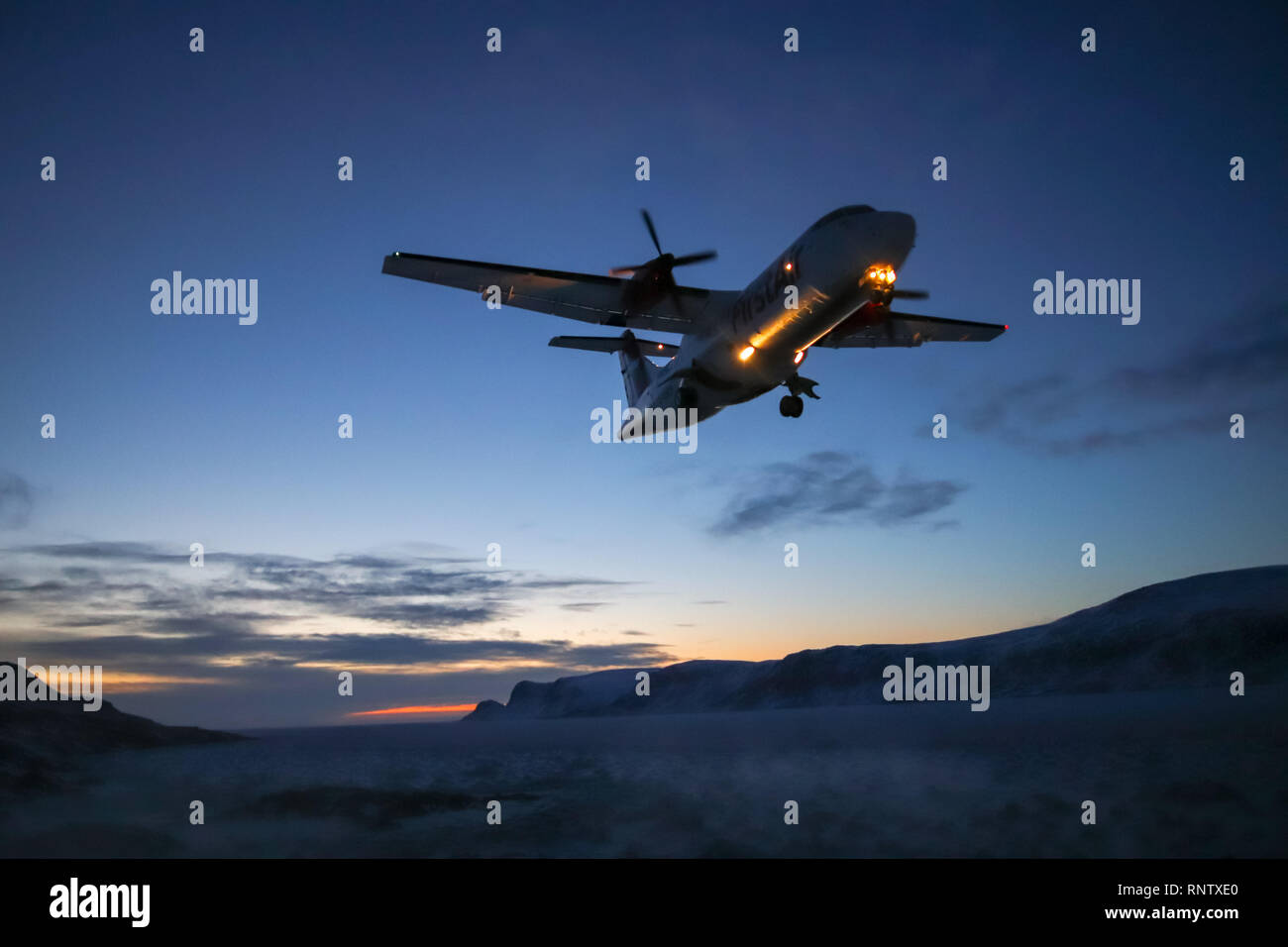 Plane coming into land at Pangnirtung Airport during a winter sunset Stock Photo