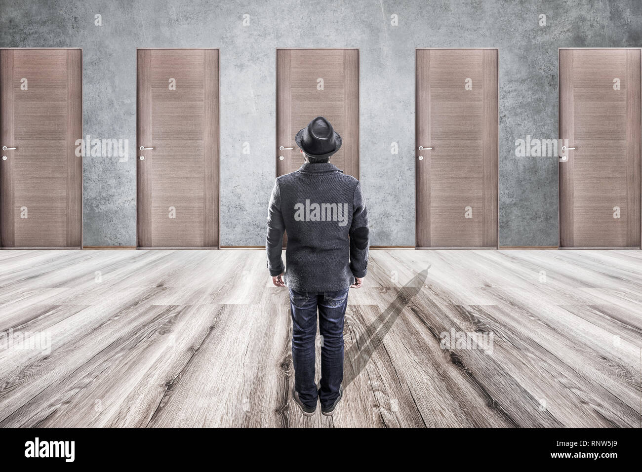 a man in a hat stands in front of wooden doors, the concept of choice and uncertainty behind closed doors Stock Photo