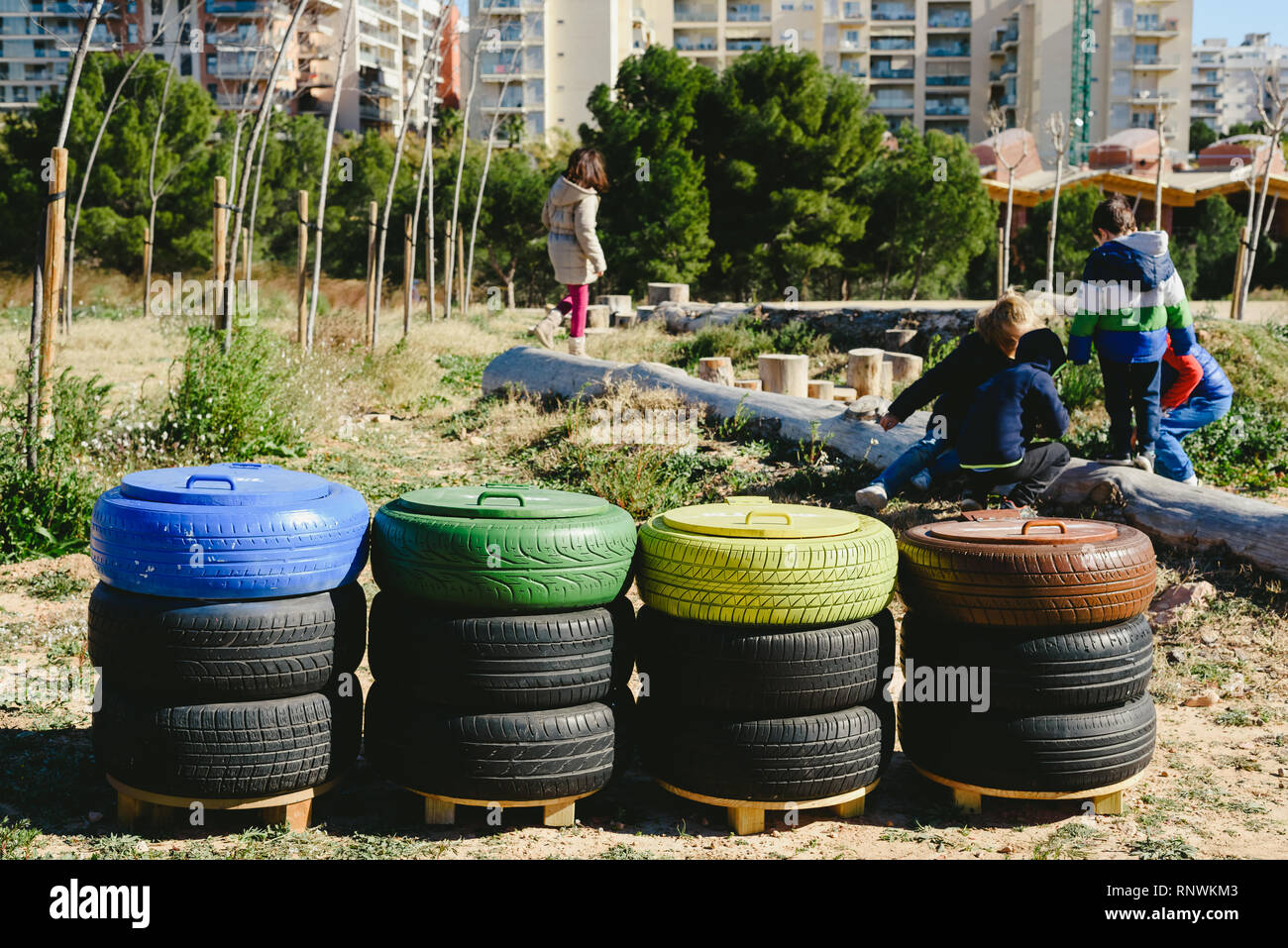 Children playing around recycling bins made with reused material Stock