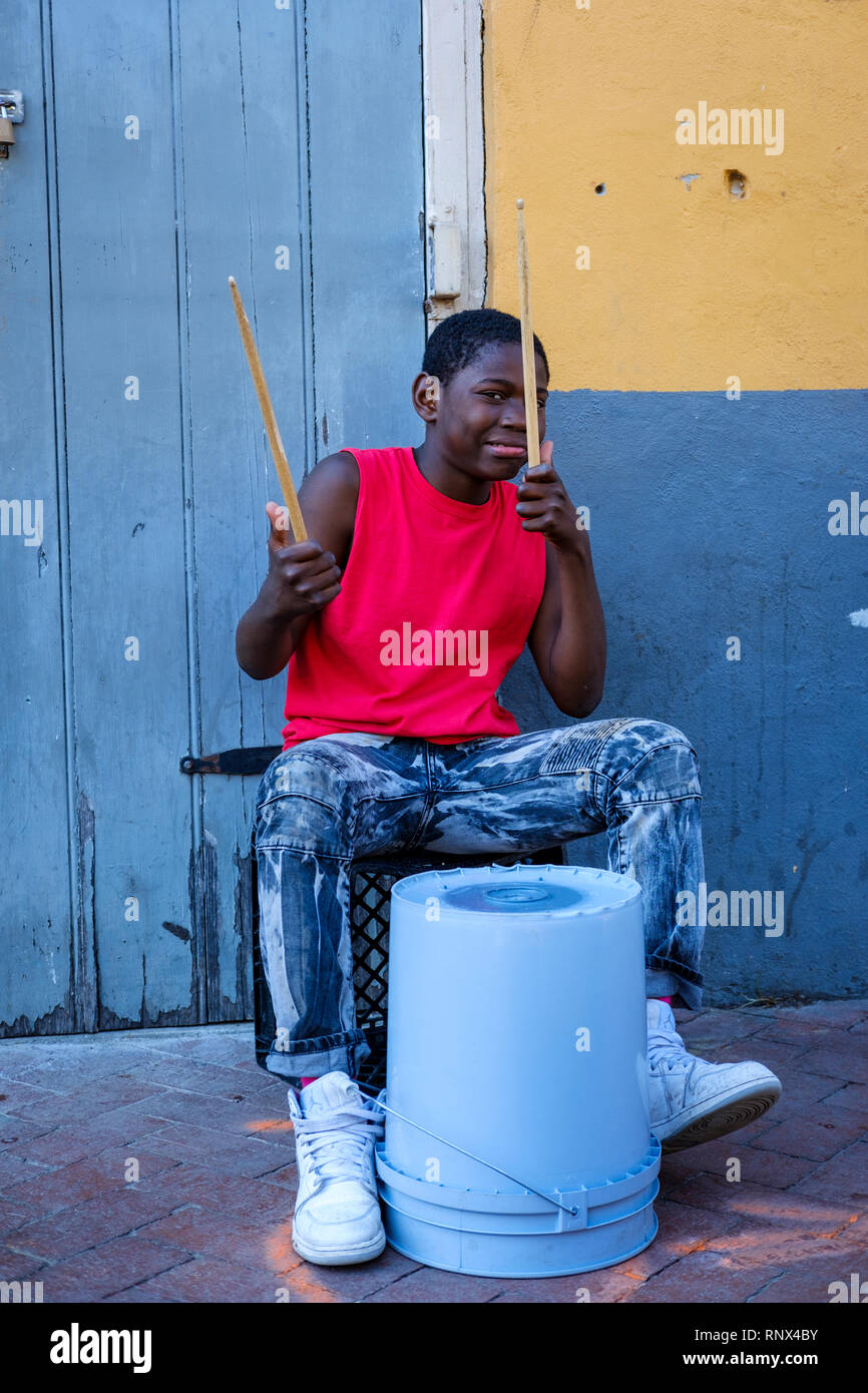 Young African-American street drummer boy drumming on a plastic bucket on Bourbon Street, New Orleans French Quarter New Orleans, Louisiana, USA Stock Photo