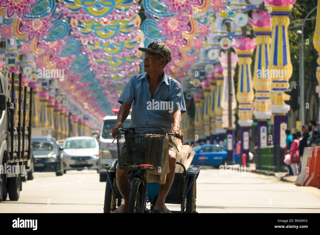 Man riding bicycle with basket in Singapore traffic - Deepavali Festival in Little India Stock Photo
