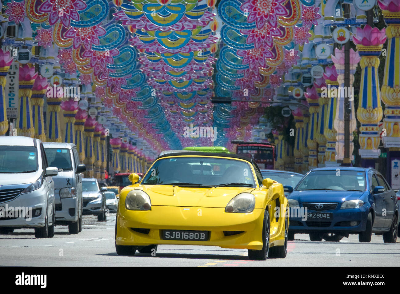 Sporty Yellow Car in traffic under Deepavali Festival Decorations - Little India, Singapore Stock Photo