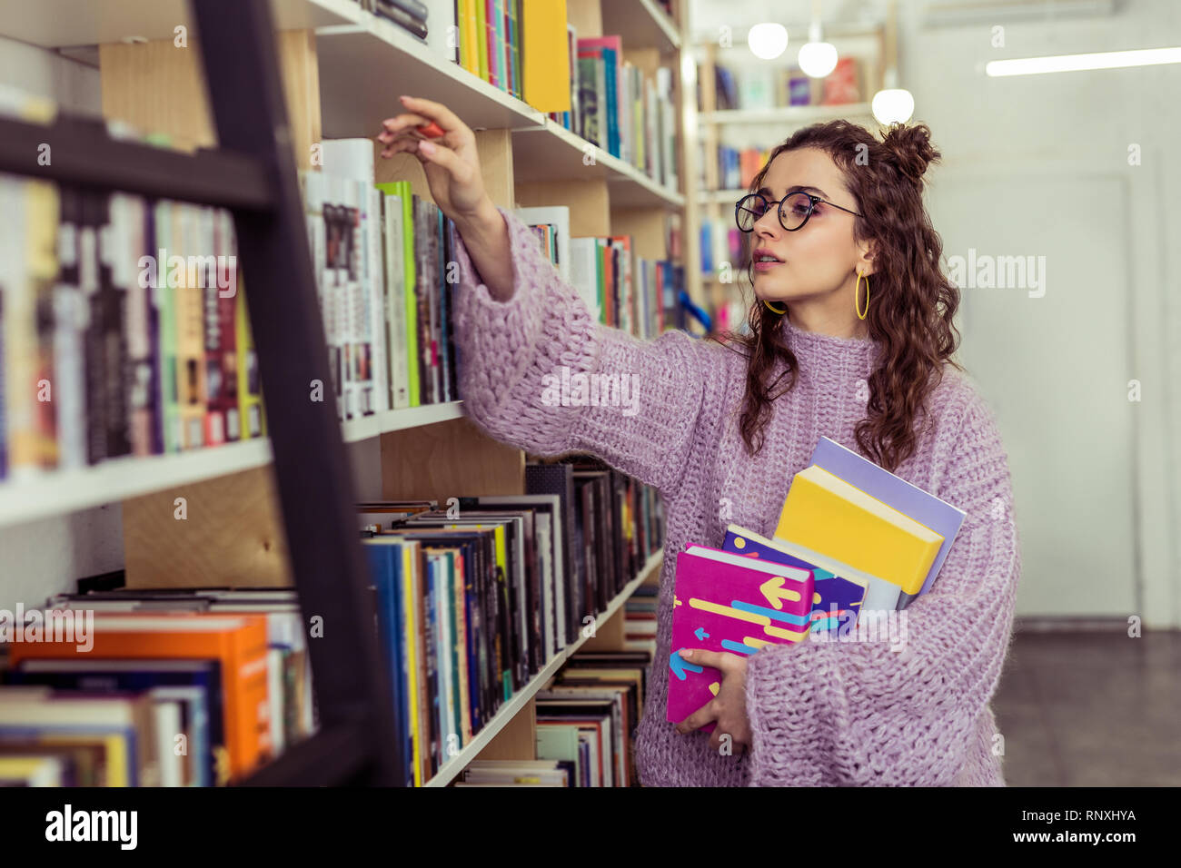 Interested appealing reader actively collecting new books Stock Photo