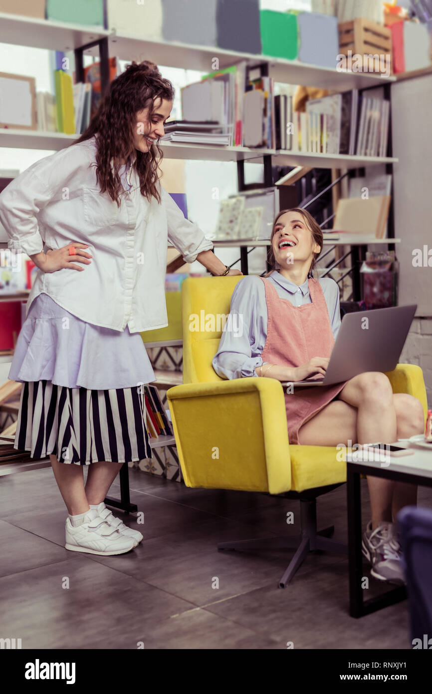 Long-haired girl in oversize outfit standing above her skinny friend Stock Photo