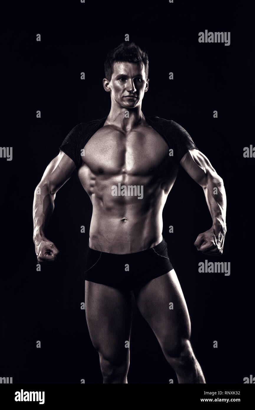 Bodybuilder show muscular body on dark background. Man sportsman with