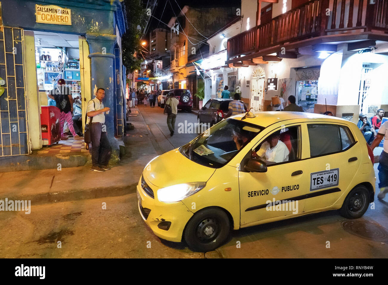 Cartagena Colombia,Center,centre,Getsemani,night evening dusk,Hispanic resident residents,street corner,doorway,car,taxi cab yellow,COL190118065 Stock Photo