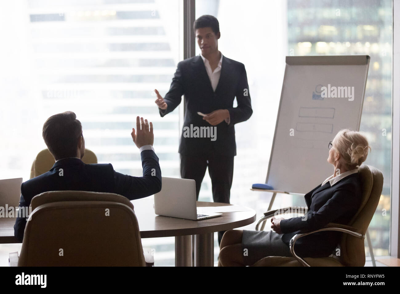 Businessman raising hand at corporate training ask questions african coach  Stock Photo