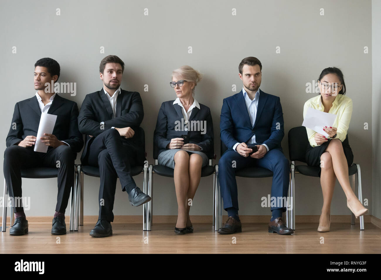 Diverse businesspeople applicants sitting in row waiting for job interview Stock Photo