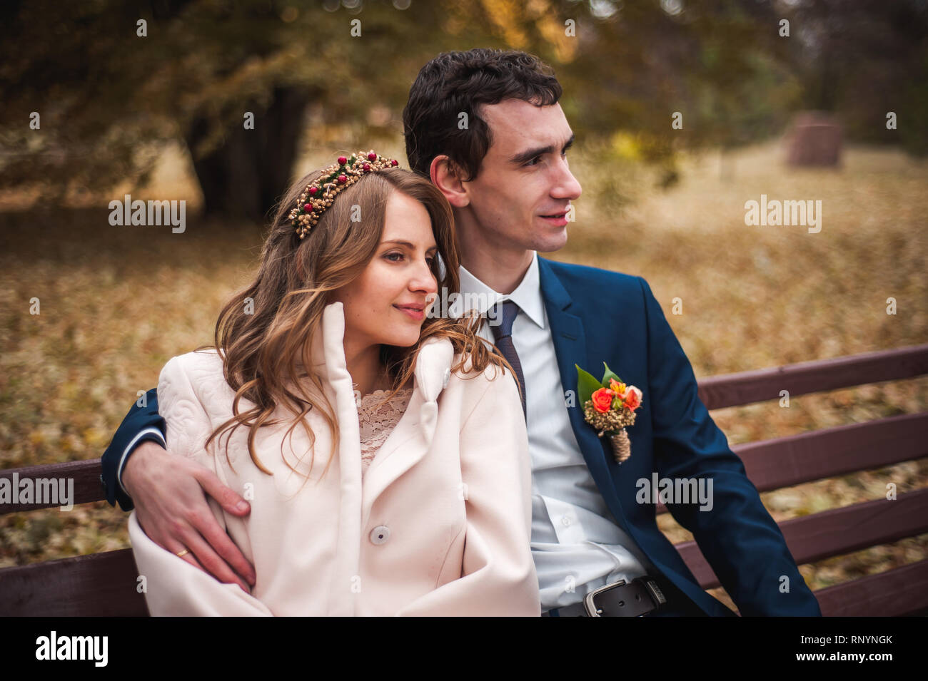 The beautiful bride and handsome groom sitting on a bench Stock Photo ...