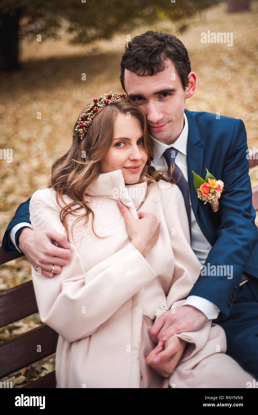 The beautiful bride and handsome groom sitting on a bench Stock Photo ...