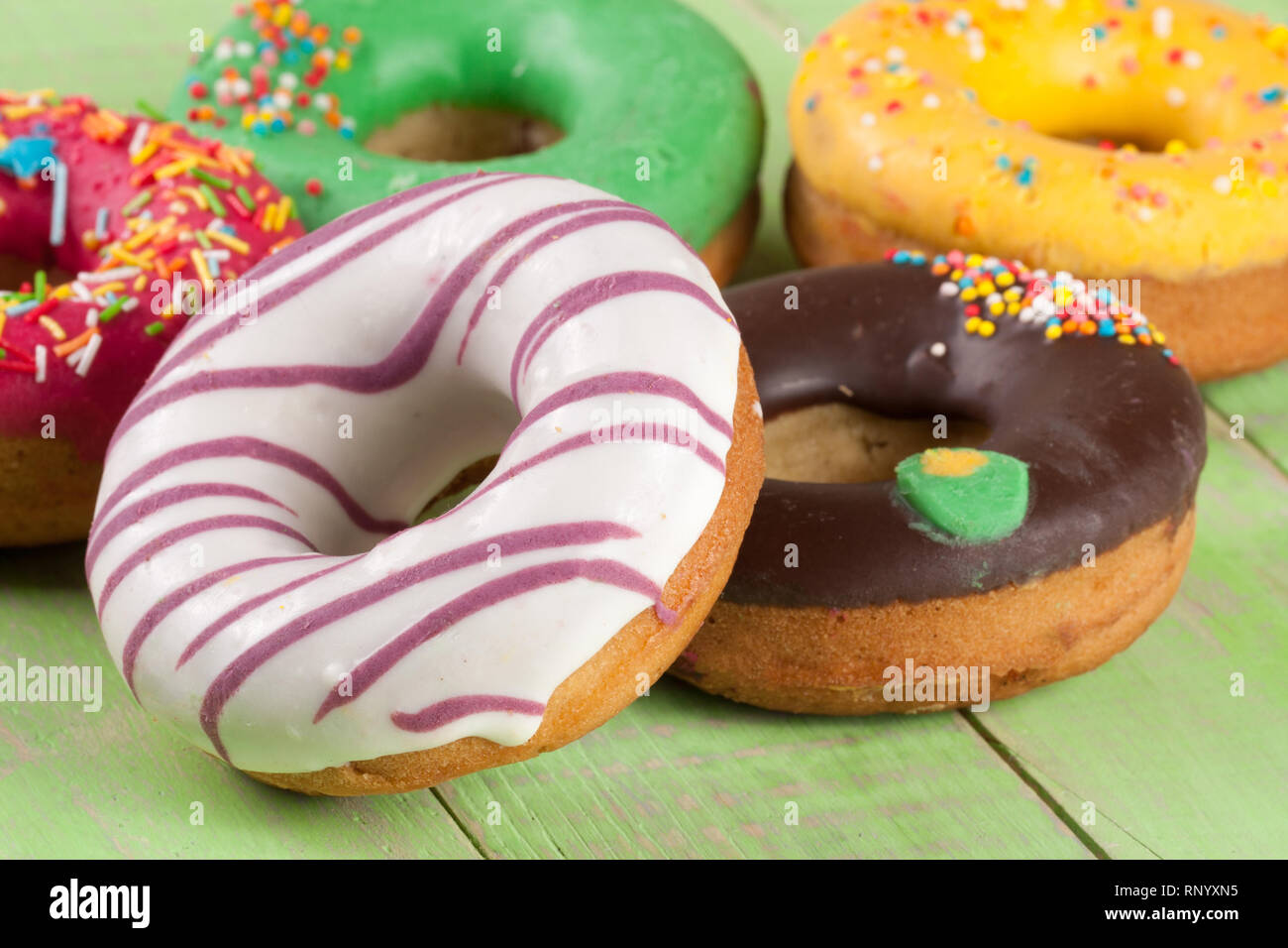 pile of glazed donuts on a green wooden background Stock Photo - Alamy