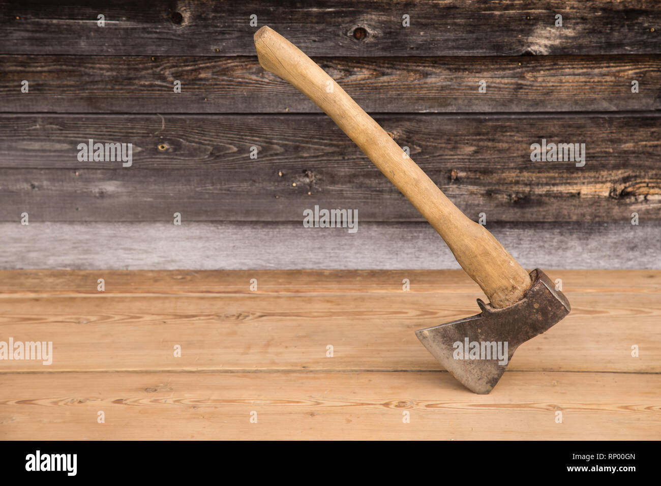 Old ax with a wooden handle stuck in wooden log. Concept for woodworking or deforestation. Selective focus. Stock Photo