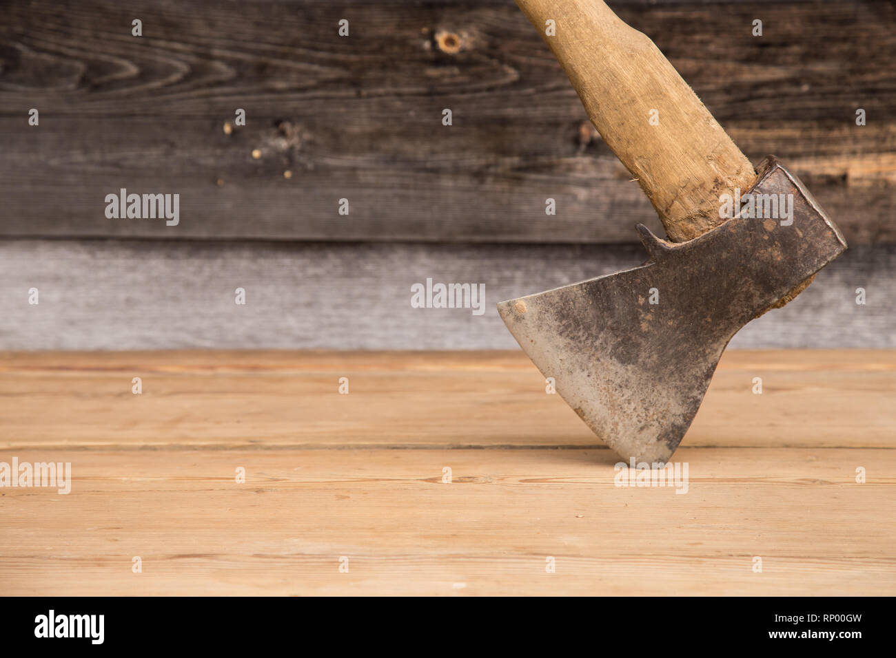 Old ax with a wooden handle stuck in wooden log. Concept for woodworking or deforestation. Selective focus. Stock Photo