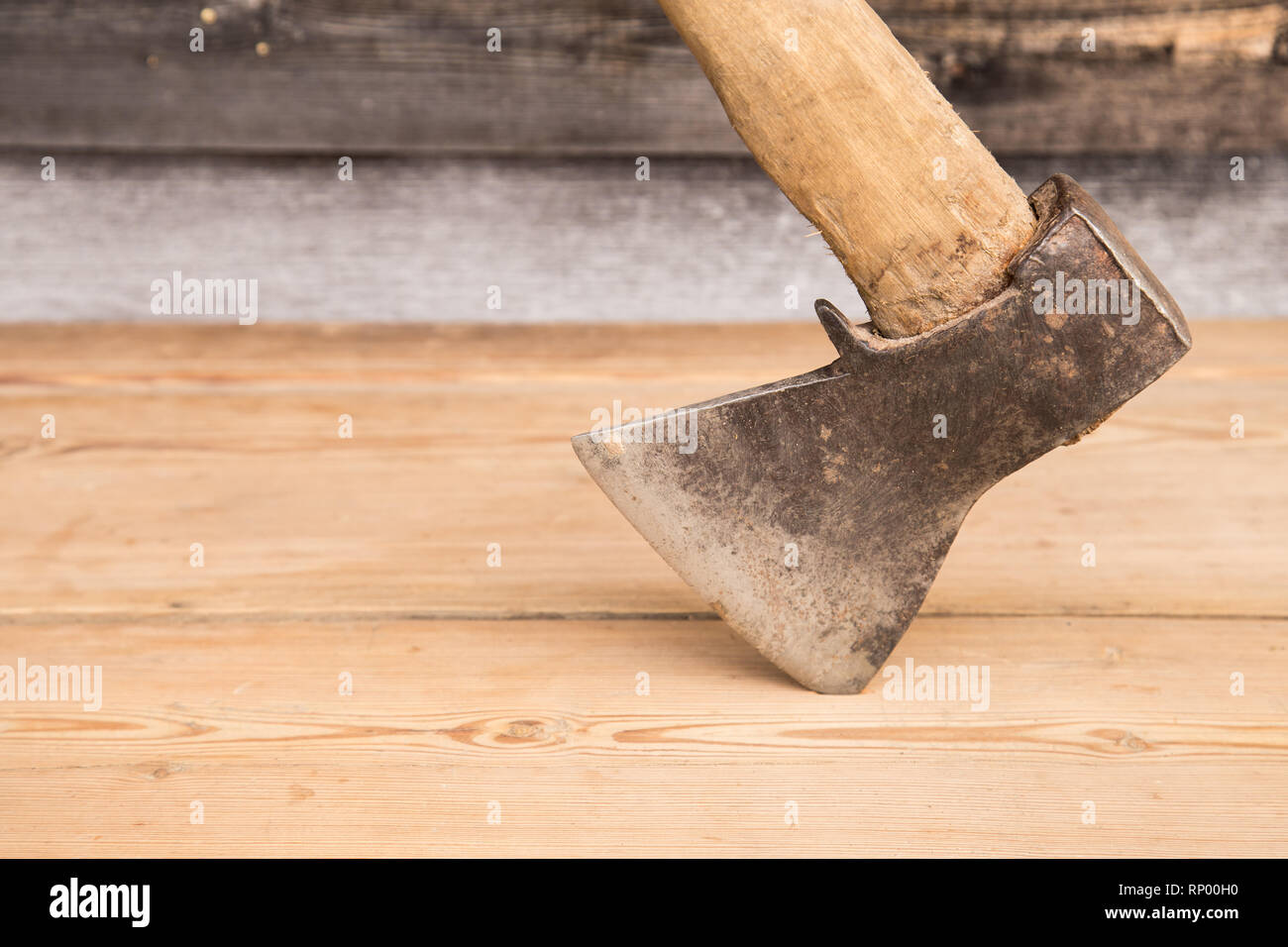 Old ax with a wooden handle stuck in wooden log. Concept for woodworking or deforestation. Selective focus. Stock Photo