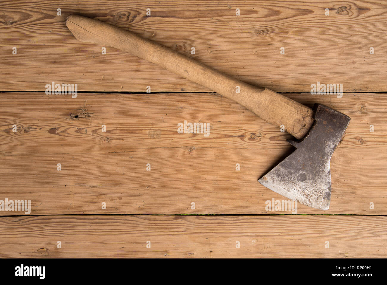 Old ax with a wooden handle stuck in wooden log. Concept for woodworking or deforestation. Selective focus. Stock Photo