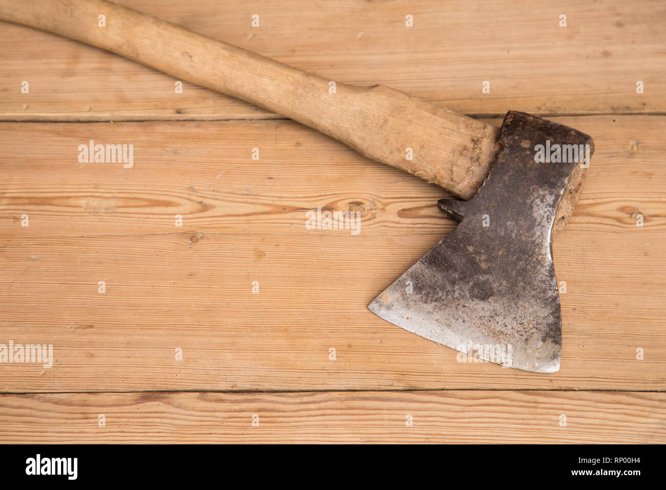 Old ax with a wooden handle stuck in wooden log. Concept for woodworking or deforestation. Selective focus. Stock Photo
