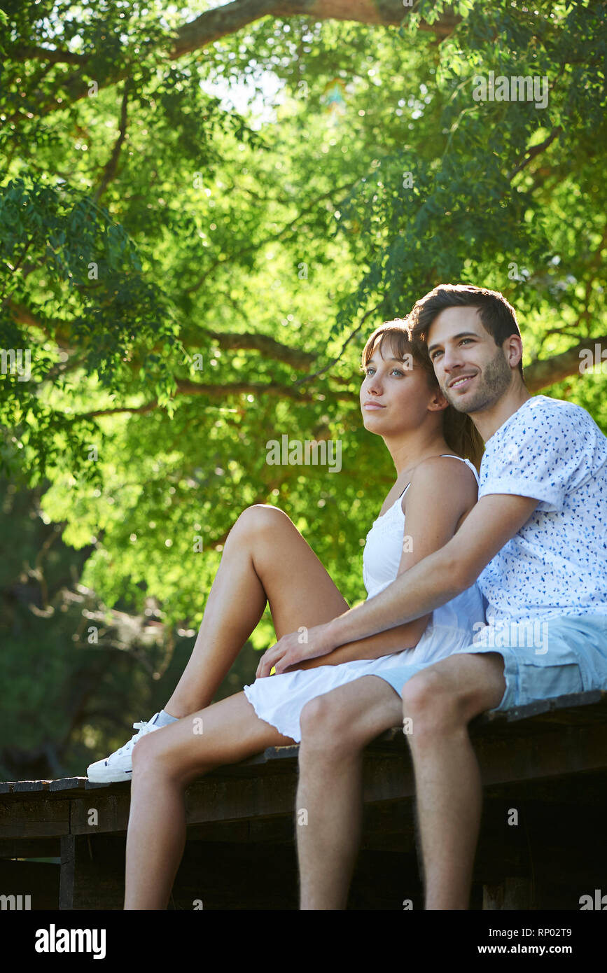 Young couple sitting in park Stock Photo - Alamy