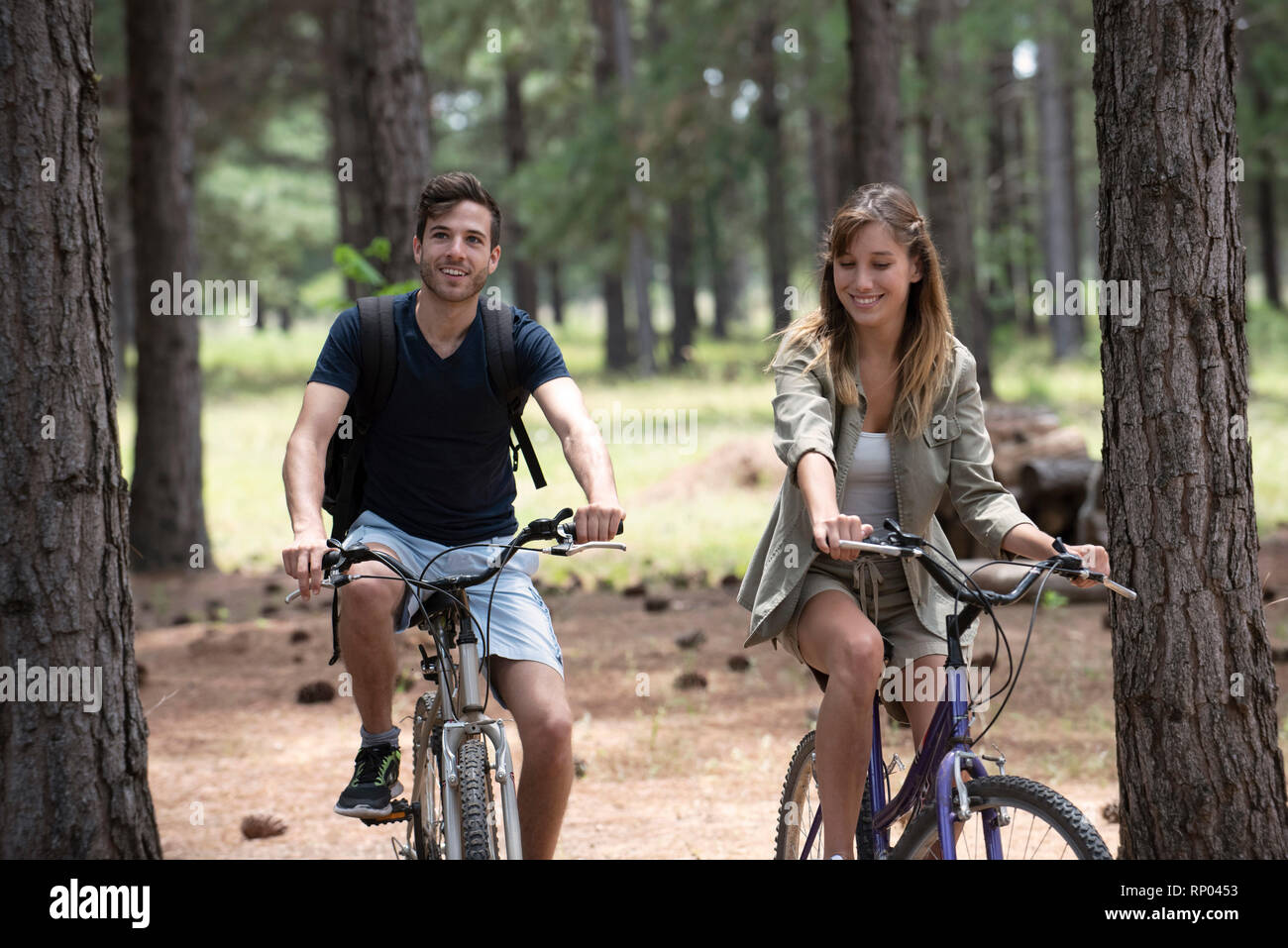 Young couple cycling in pine forest Stock Photo
