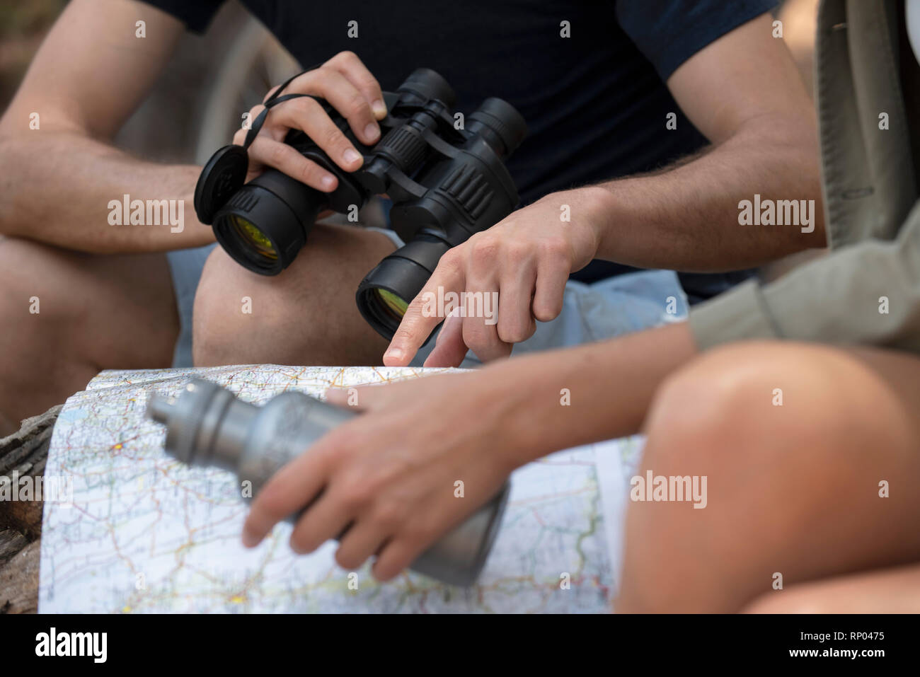 Young couple reading map while sitting in the forest Stock Photo