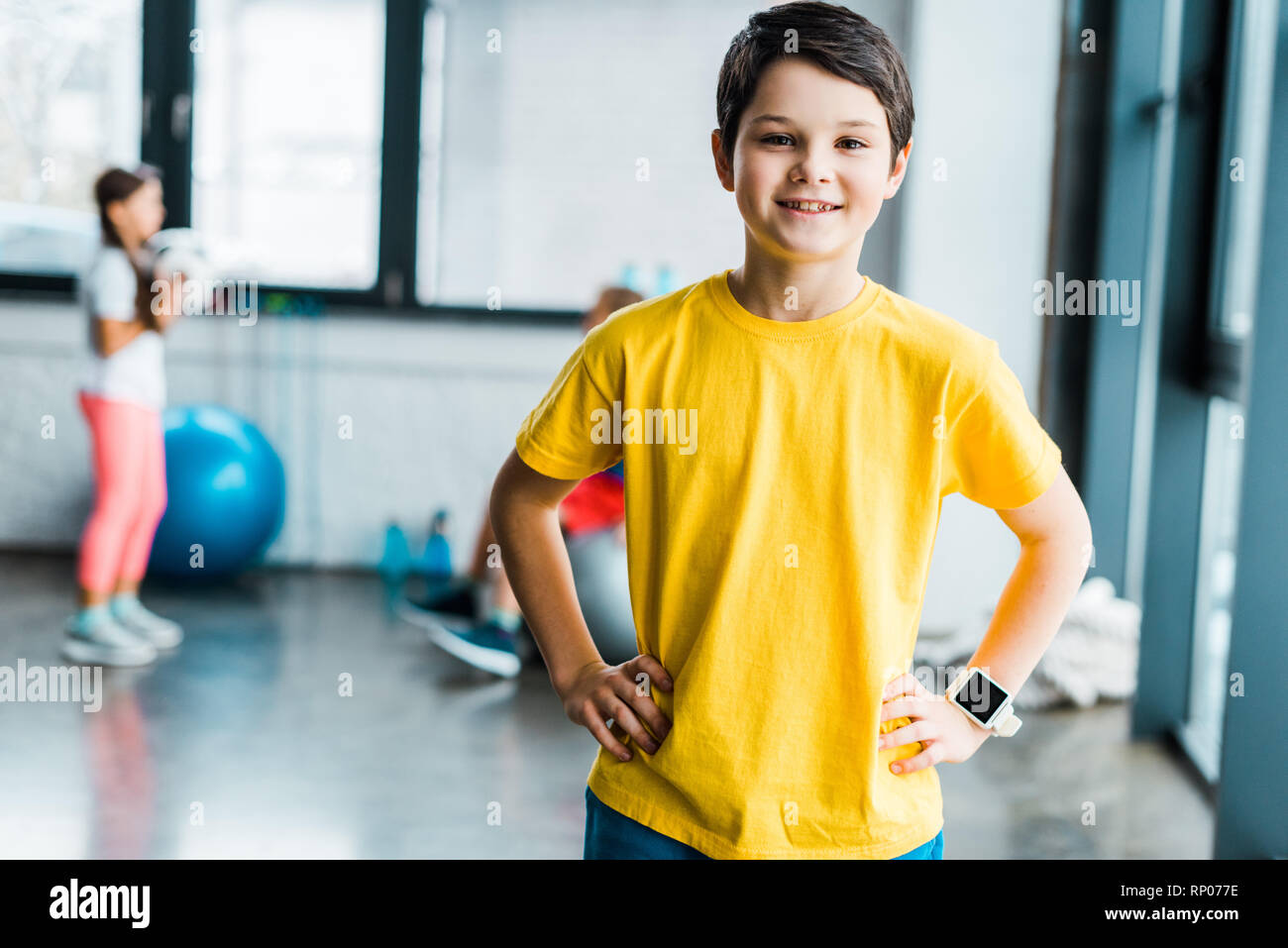 Smiling brunette boy posing with arms akimbo in gym Stock Photo - Alamy