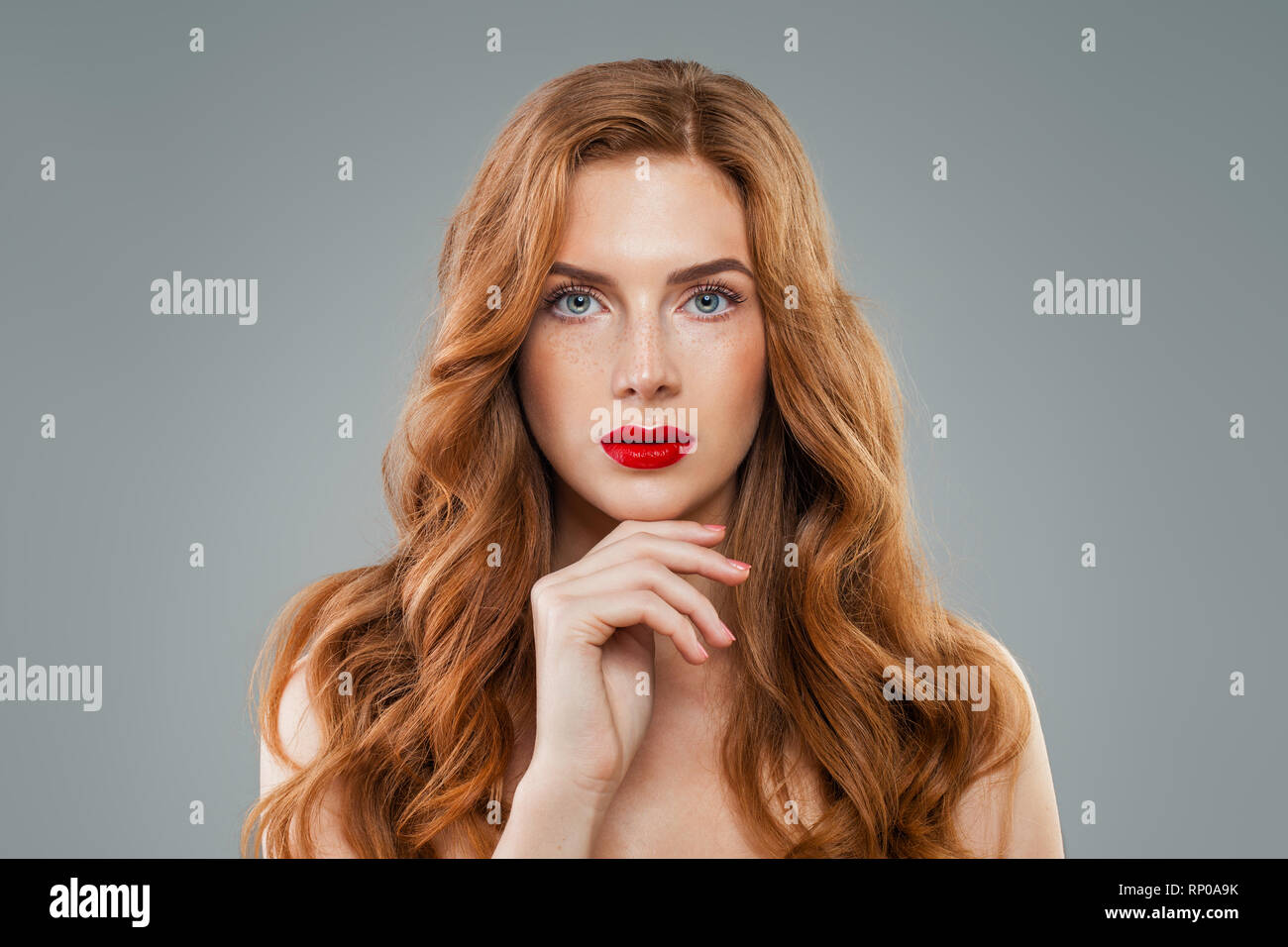 Beautiful model with long curly red hair looking at camera. Wavy shiny